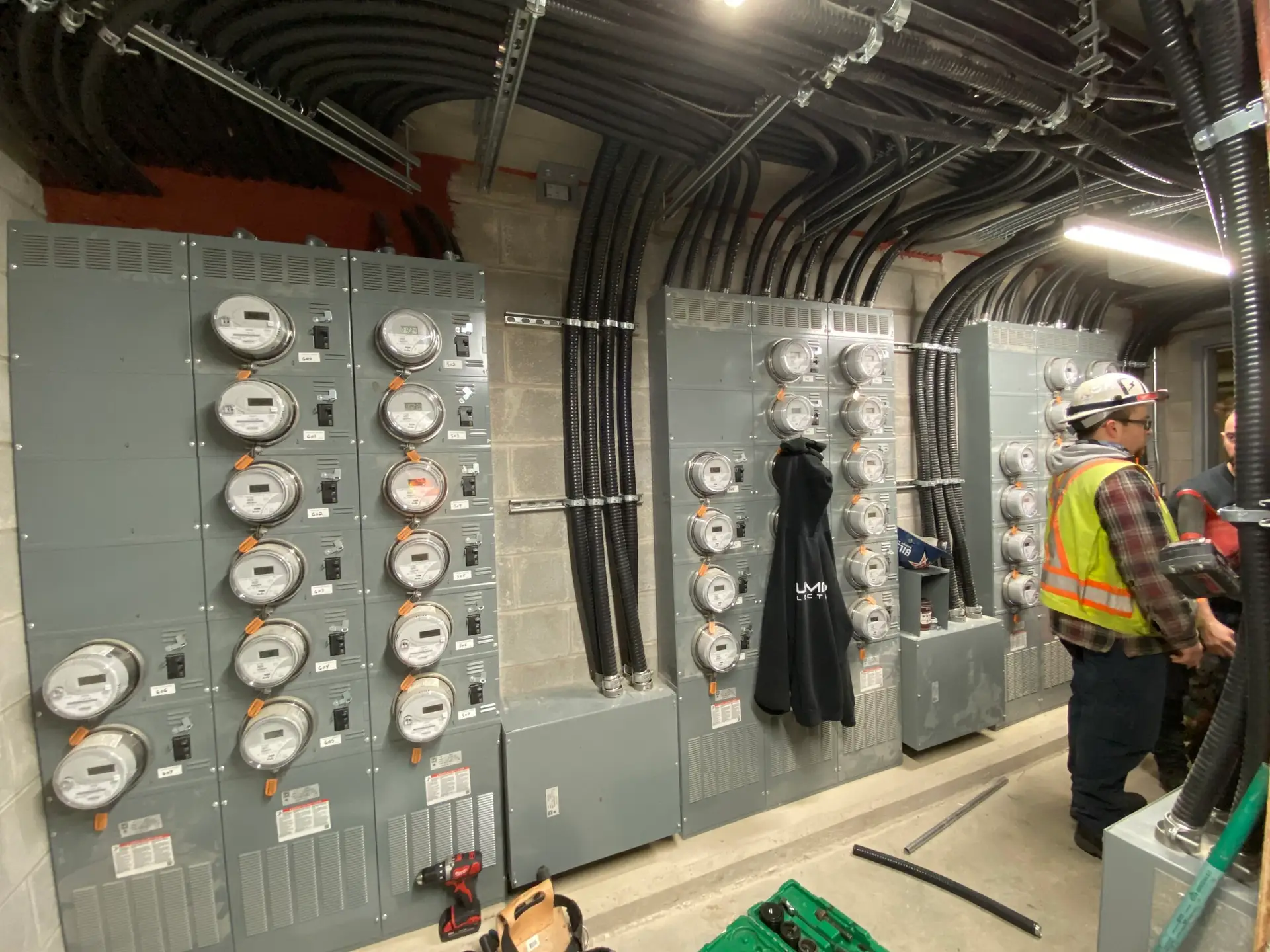 Un travailleur de LuMar Electric en veste haute visibilit&eacute; devant un ensemble de compteurs commerciaux