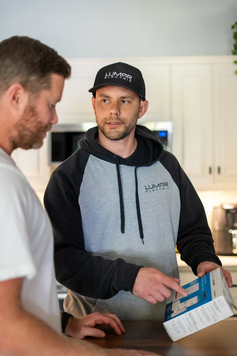 LuMar electrician explaining a new smart switch to a homeowner in his kitchen