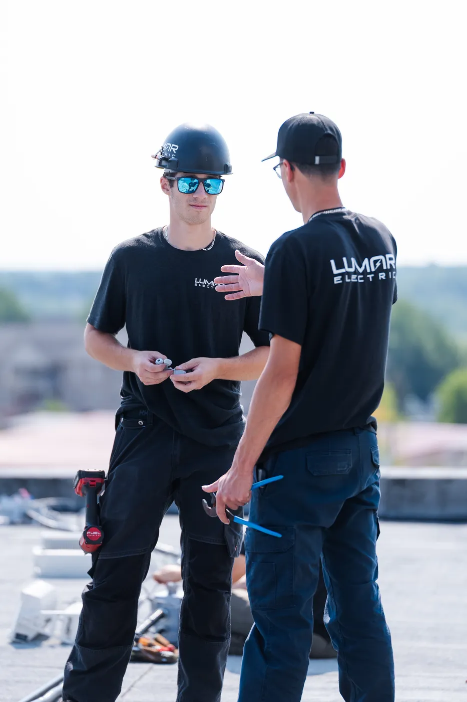 Two LuMar Electric electricians working together on a rooftop