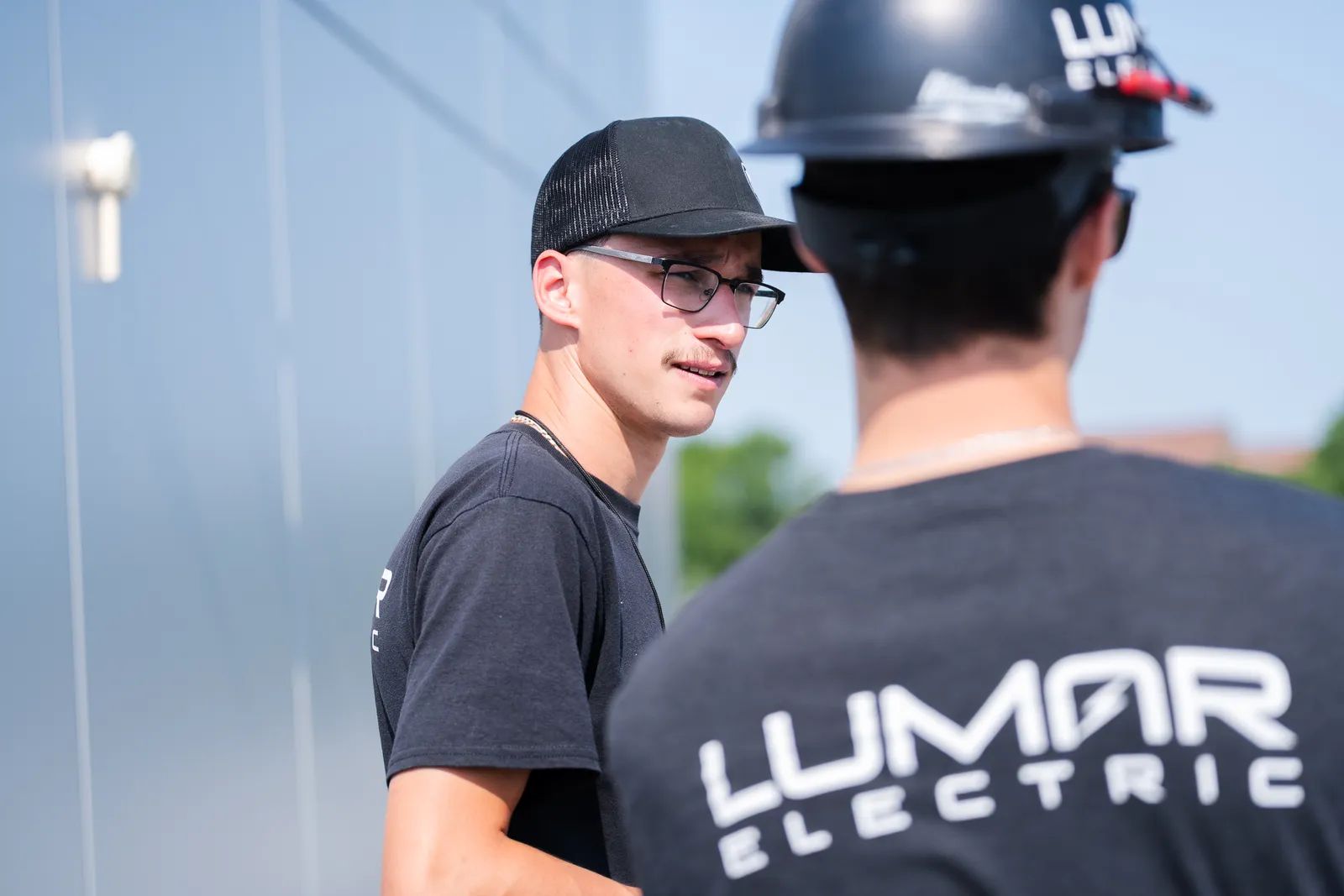 Deux &eacute;lectriciens de LuMar Electric discutant sur un chantier