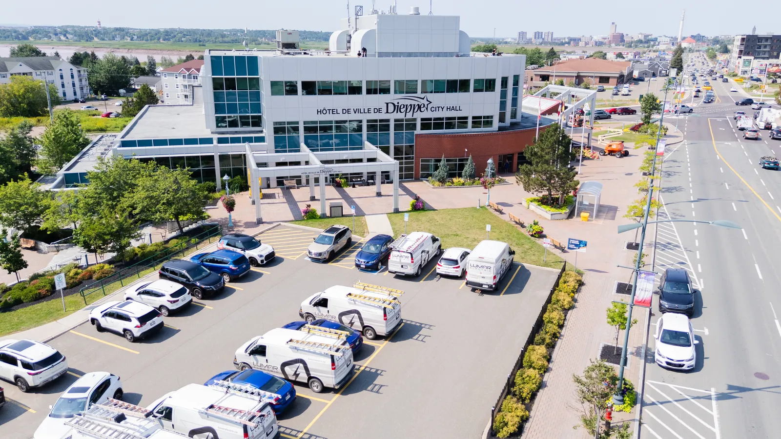 Dieppe City Hall in daylight with LuMar Electric vans parked outside