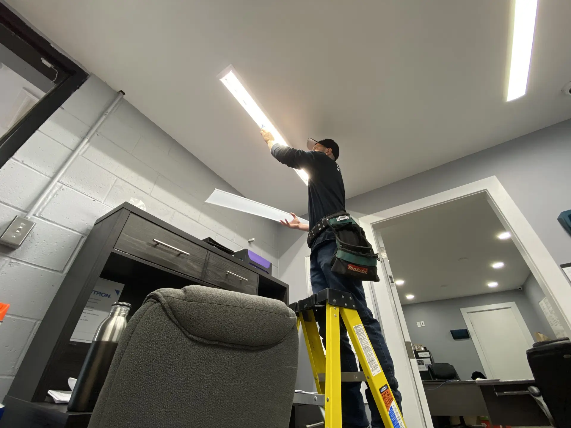 Technicien de LuMar Electric r&eacute;parant l&rsquo;&eacute;clairage d&rsquo;un local commercial