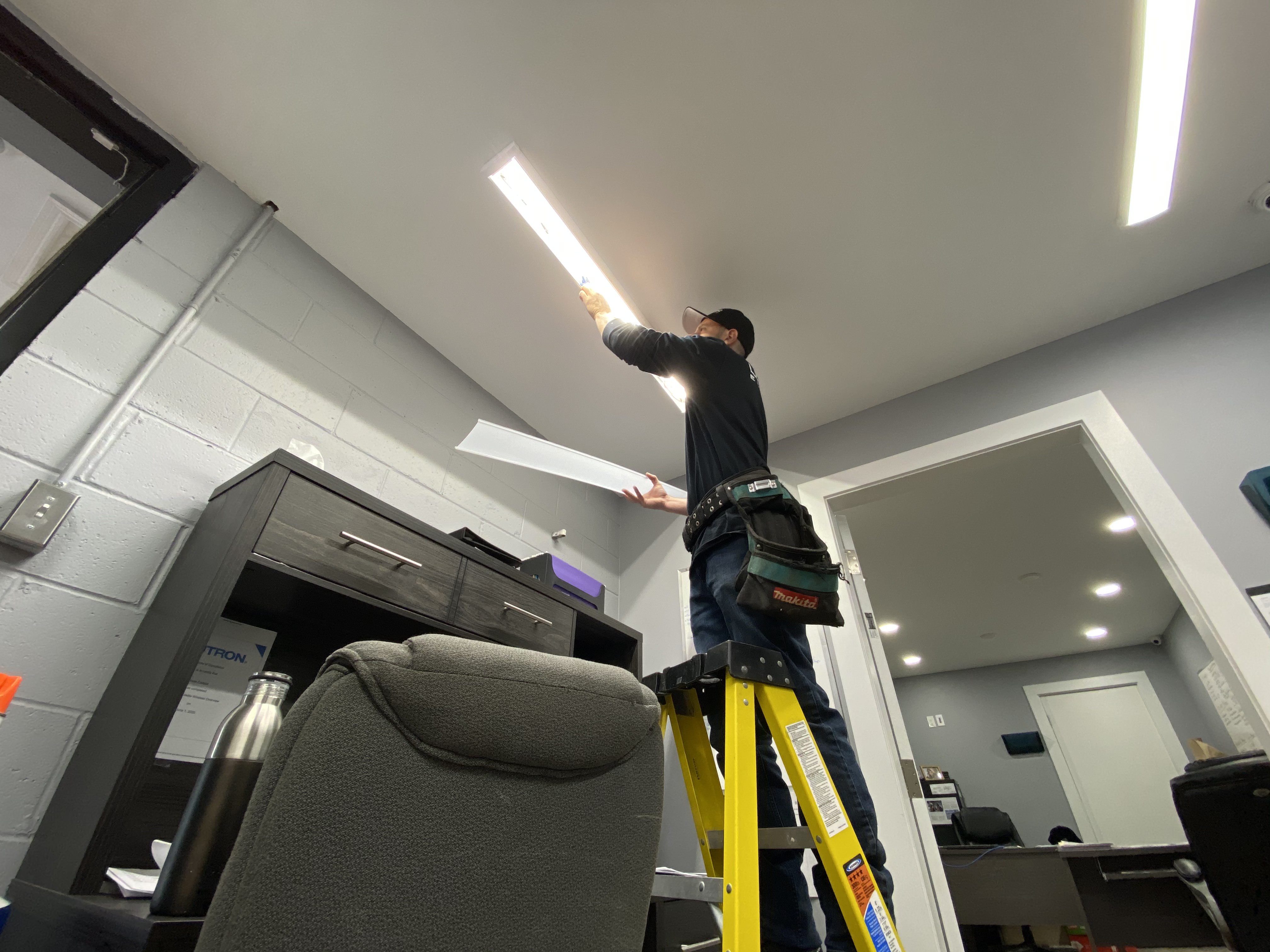 LuMar Electric electrician installing an LED fixture in a commercial office