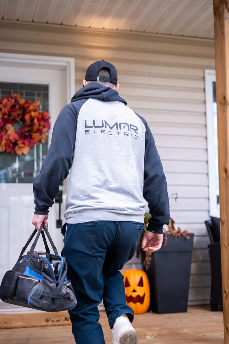 LuMar Electric technician arriving at a customer&rsquo;s front door with his tool bag