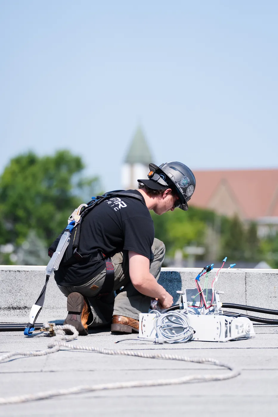 A LuMar Electric electrician making up connections on a rooftop parapet above the street