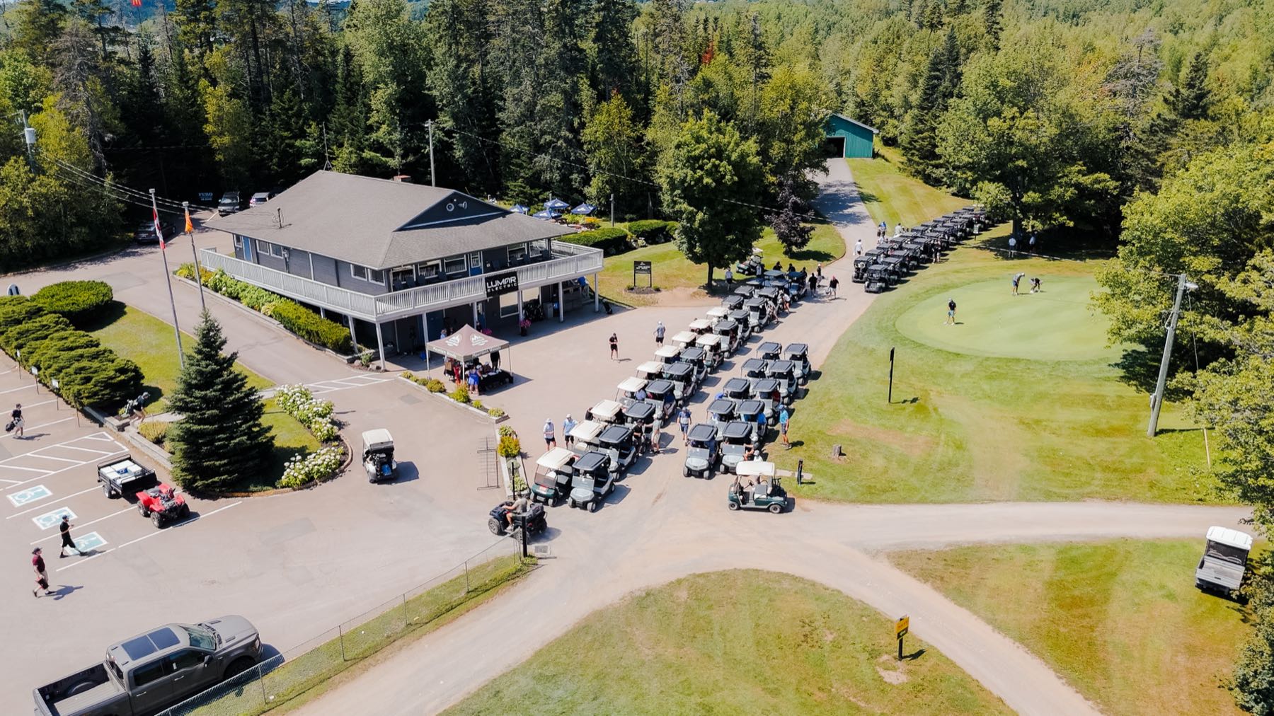 Voiturettes align&eacute;es devant le pavillon de Pine Needles lors du tournoi de golf de LuMar Electric
