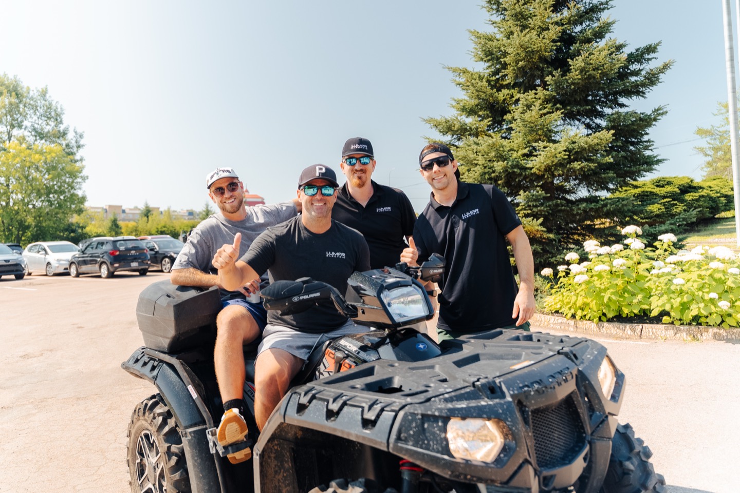 Quatre membres de l&rsquo;&eacute;quipe de LuMar Electric autour d&rsquo;un VTT dans le stationnement du pavillon