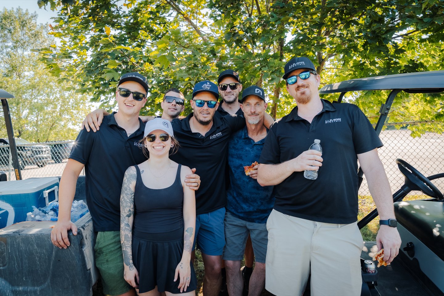 Un groupe d&rsquo;employ&eacute;s de LuMar Electric r&eacute;unis pr&egrave;s d&rsquo;une voiturette lors du tournoi annuel