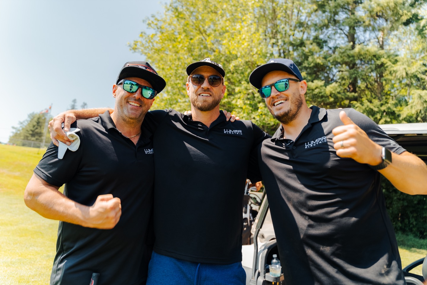Trois membres de l&rsquo;&eacute;quipe de LuMar Electric en polo de l&rsquo;entreprise pr&egrave;s d&rsquo;une voiturette