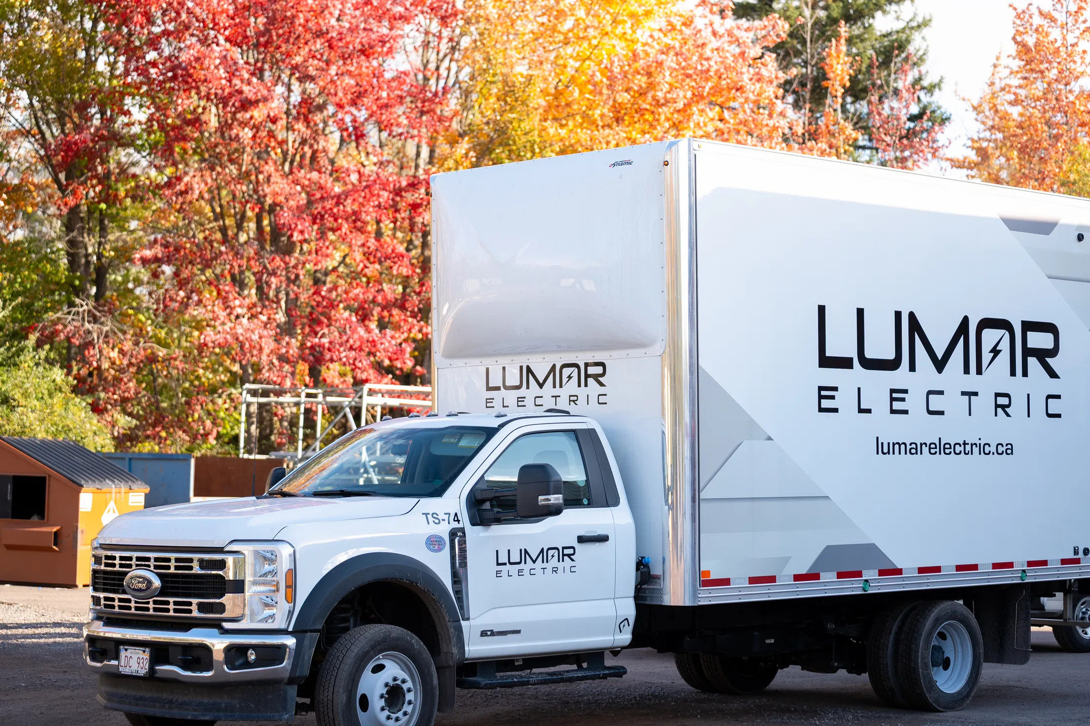 A LuMar Electric truck parked under autumn trees