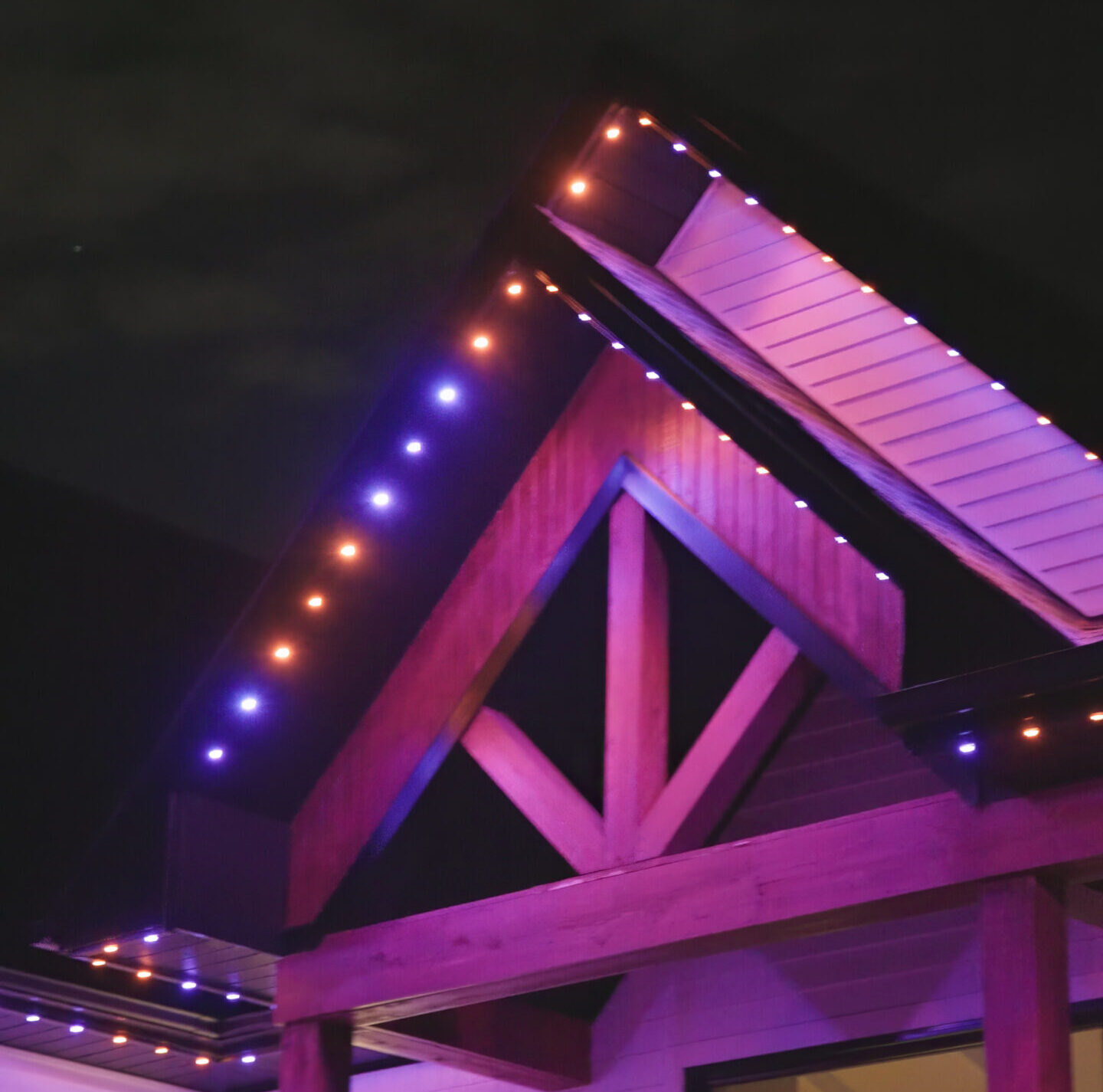 A roofline lit in purple and orange by permanent outdoor LED lighting