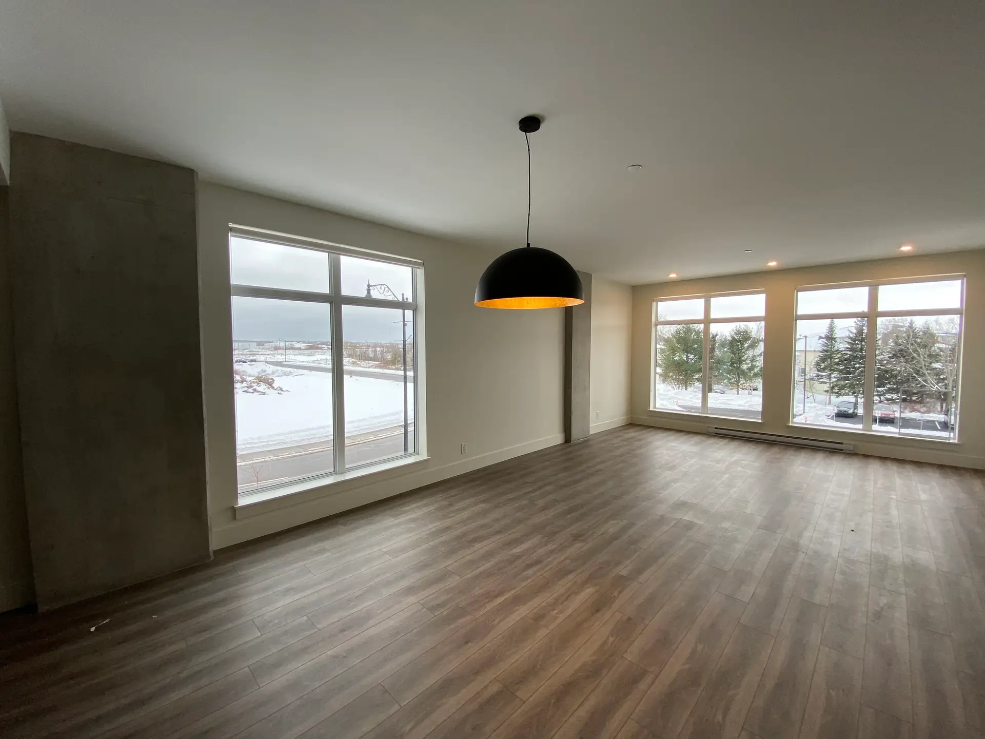 Spacious room with large windows and wooden floor.