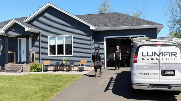 Electricians working outside a blue house with van.