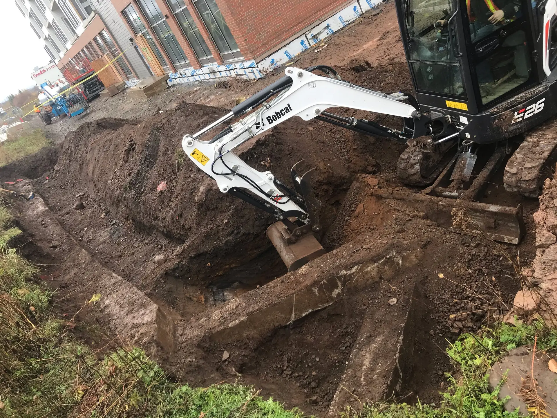Excavator digging trench on construction site.