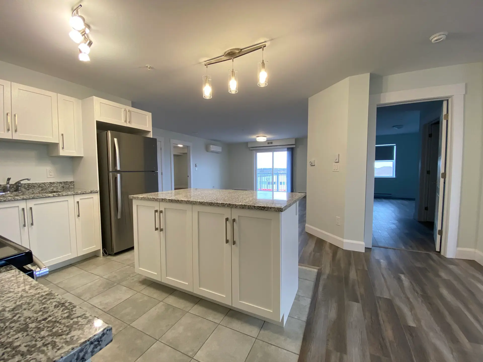 Modern kitchen with granite island and stainless appliances.